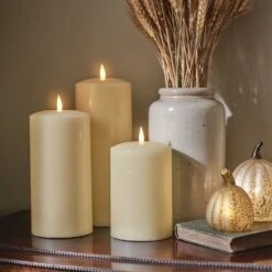 Lot De 3 Bougies Cierges à LED TruGlow® 15 Lot De 3 Bougies Cierges à LED TruGlow® -Noel Deco Magasin une table de chevet decoree avec un trio de bougie cierge et des citrouilles lumineuses